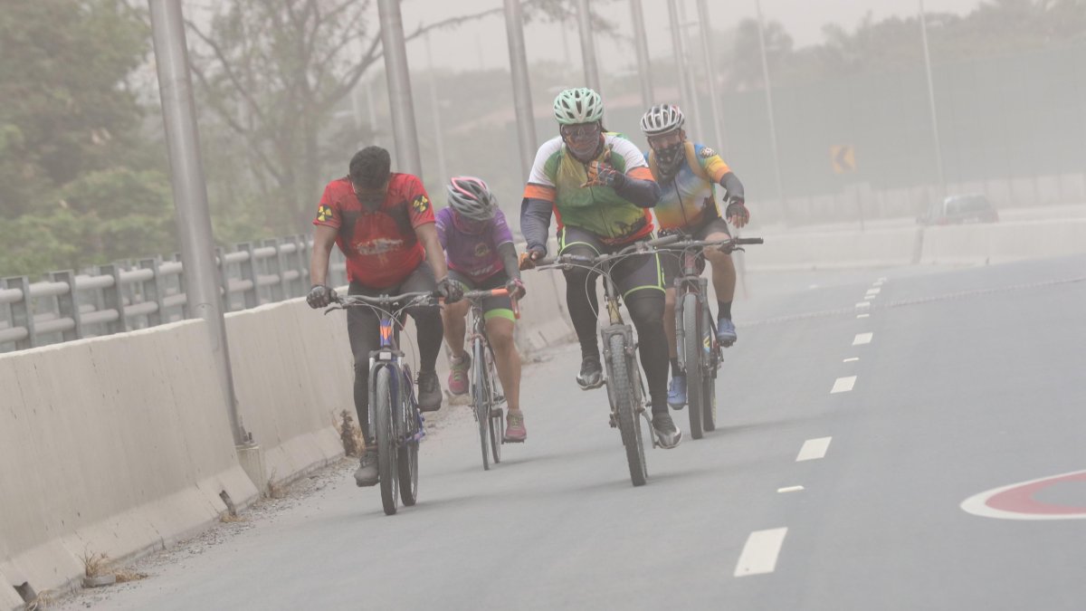Ciclistas conducen en medio de las partículas del Sangay, en Guayaquil.