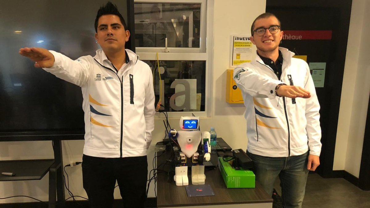 Brian Pinos (​i) junto a Víctor Uguña (d) mostrando el prototipo del robot que imita los movimientos de terapias físicas.