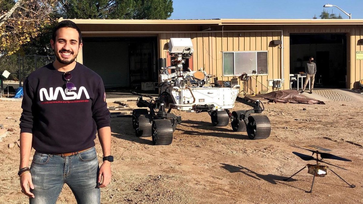 Elio Morillo junto al Rover Perseverance y el helicóptero Ingenuity en las instalaciones del Laboratorio de propulsión a chorro de la NASA.