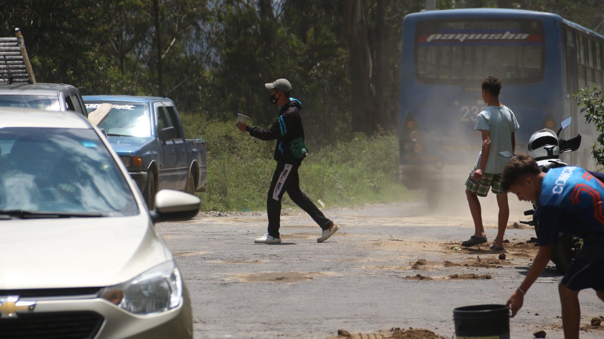 Los extranjeros aprovechan los enormes baches en la vía para rellenarlos y ganar algo de dinero.