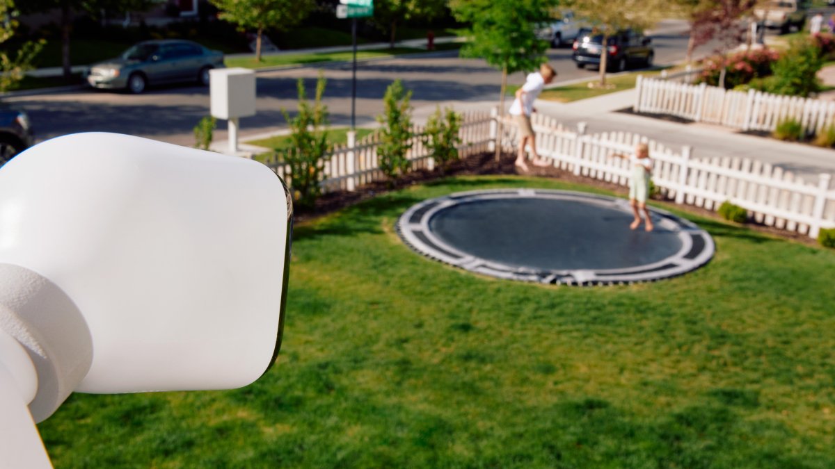 Observación. Dos niños juegan en el área frontal de una casa, mientras son supervigilados por una cámara.