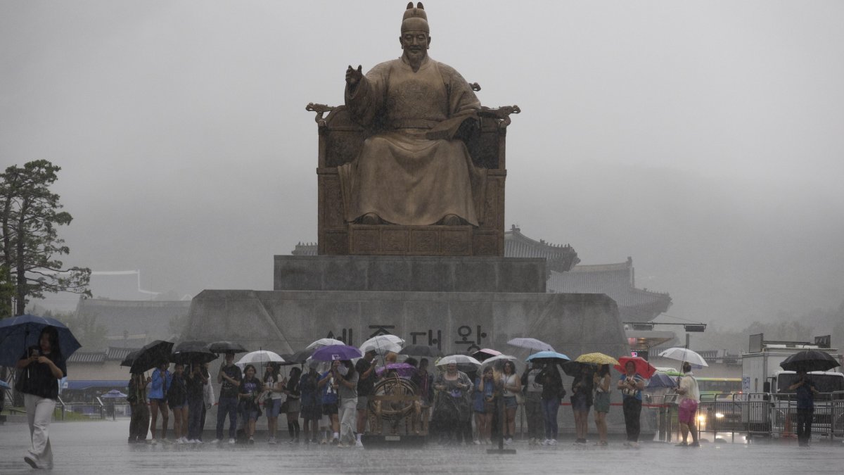 La gente camina con paraguas en medio de una fuerte lluvia en la plaza Gwanghwamun en Seúl, Corea del Sur, el 17 de julio de 2024. (Corea del Sur, Seúl)