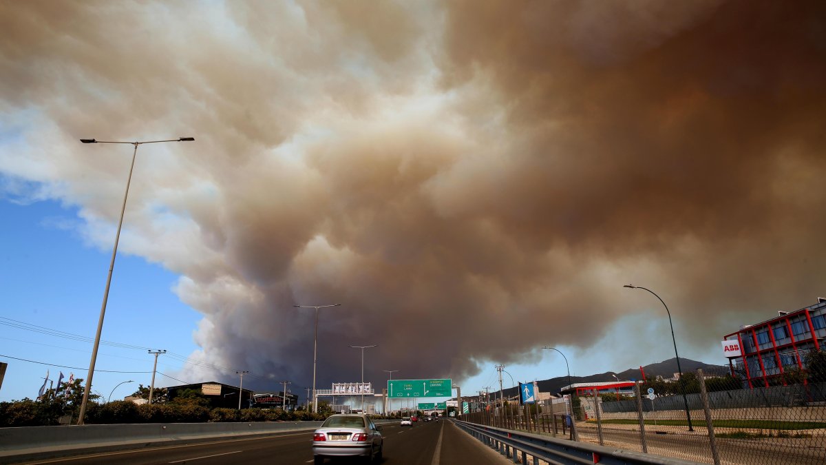Un espeso humo cubre la carretera nacional en Atenas debido a un incendio forestal que estalló en una zona de tierras de cultivo y bosque en Varnavas, región de Ática, Grecia.