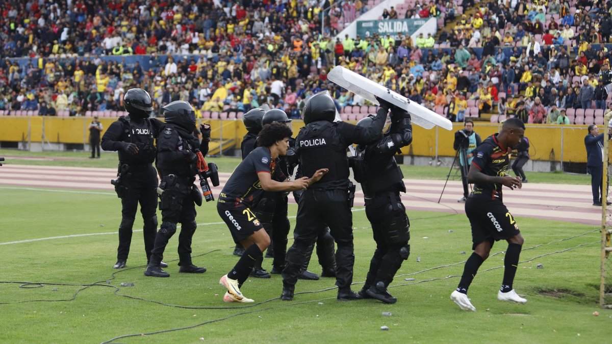 Los futbolistas Eduard Bello (i) y Dixon Arroyo (d) se protegen de los huevos y demás objetos que les arroja la hinchada torera en el estadio Olímpico Atahualpa.
