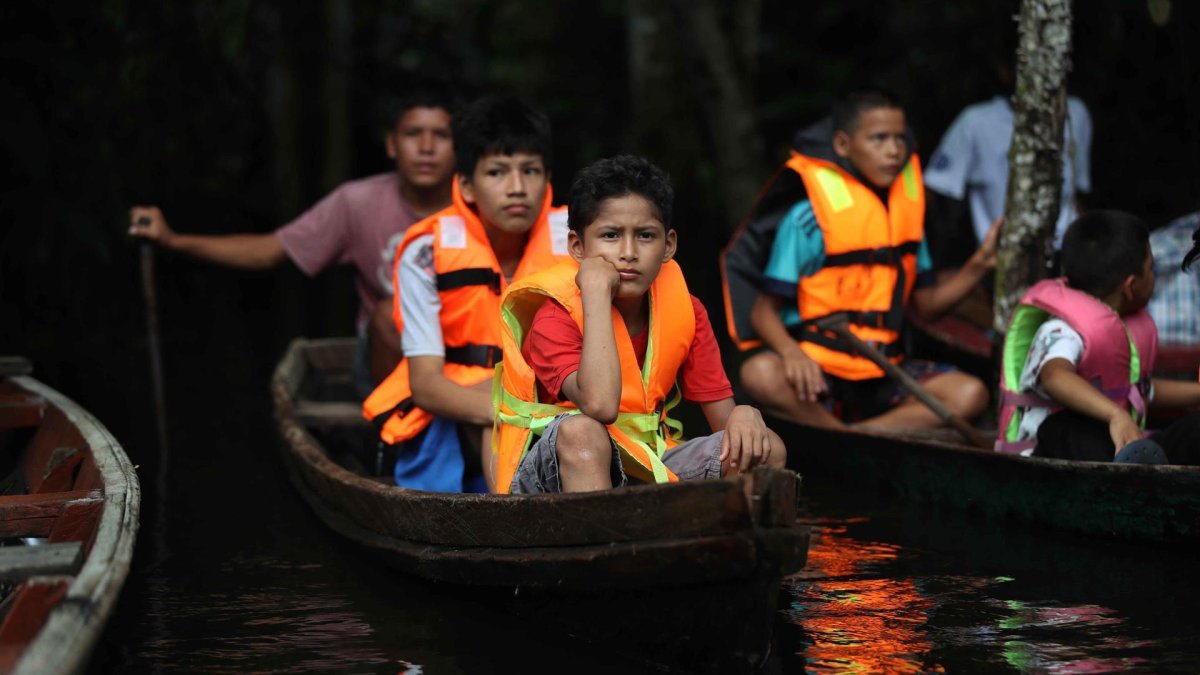 Un grupo de niños en canoas dirigiéndose a un vivero por el rio Itaya, en Iquitos (Perú).