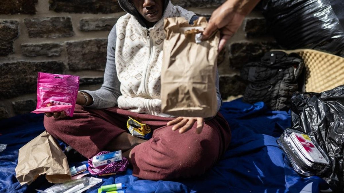 Genese Hubbard, asesora de recuperación en el Centro de Empleo Nuestro Pan Diario, reparte suministros y Narcan a una mujer sin hogar en Baltimore, Maryland.