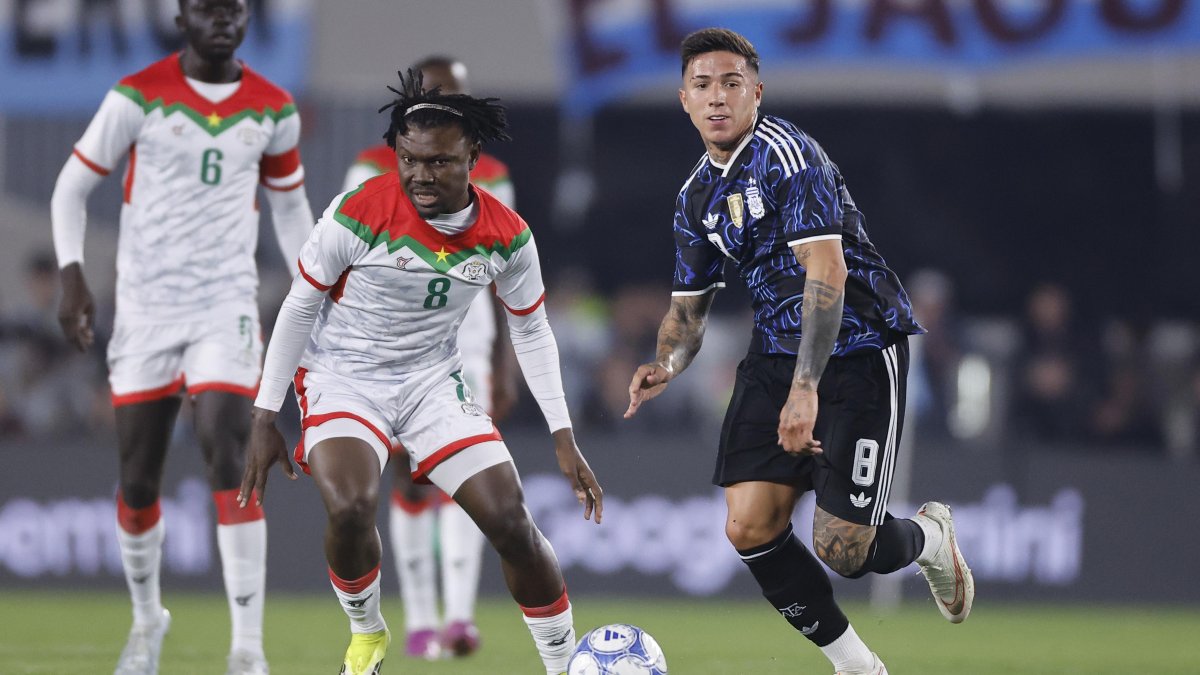Enzo Fernández (d) de Argentina disputa el balón con Alain Kanté de Burkina Faso.