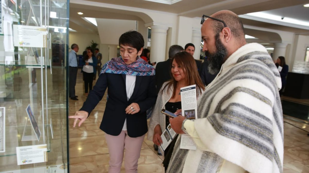 Invitados observan fotografías que se exhiben sobre el tema migratorio, en la Cancillería