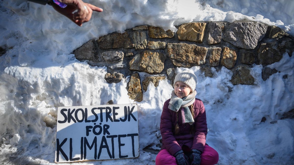 DAVOS. La activista juvenil sueca por el clima Greta Thunberg se sienta junto a un cartel que dice 