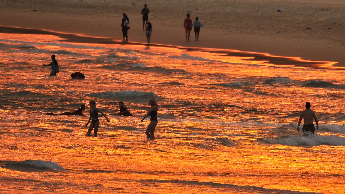 Bañistas disfrutan del atardecer en la playa de Bondi durante una ola de calor en Sydney