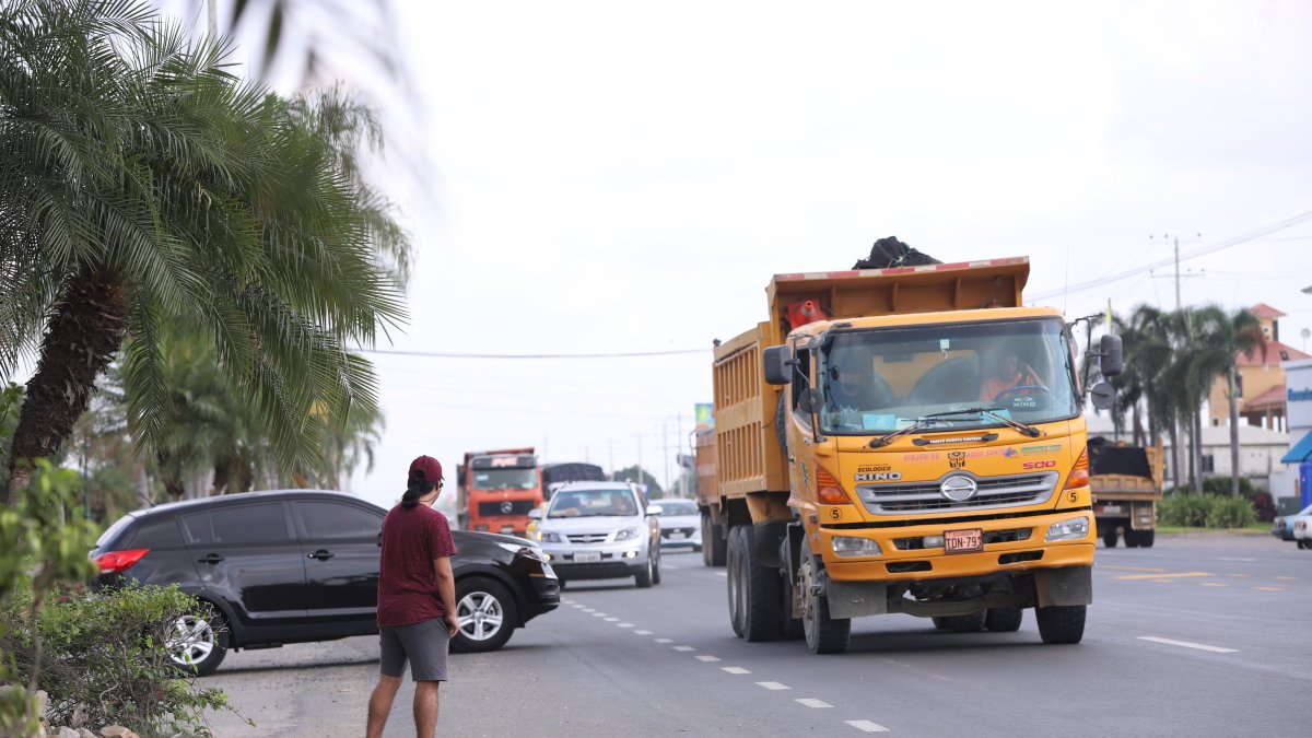 Un joven intenta cruzar la arteria. A la vez, un auto intenta entrar a una urbanización y otro salir de ella. 