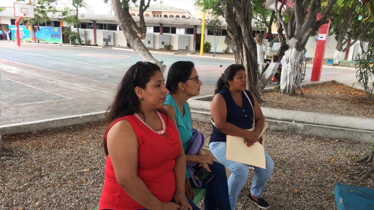 Las madres esperan a que sus hijos rindan el examen, en los exteriores de la unidad educativa Provincia de Tungurahua, en el norte de Guayaquil.