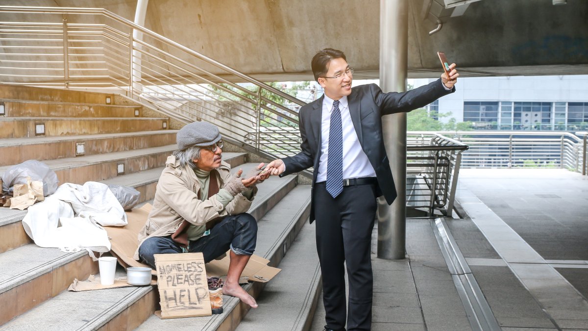 Empresario tomándose foto con mendigo.