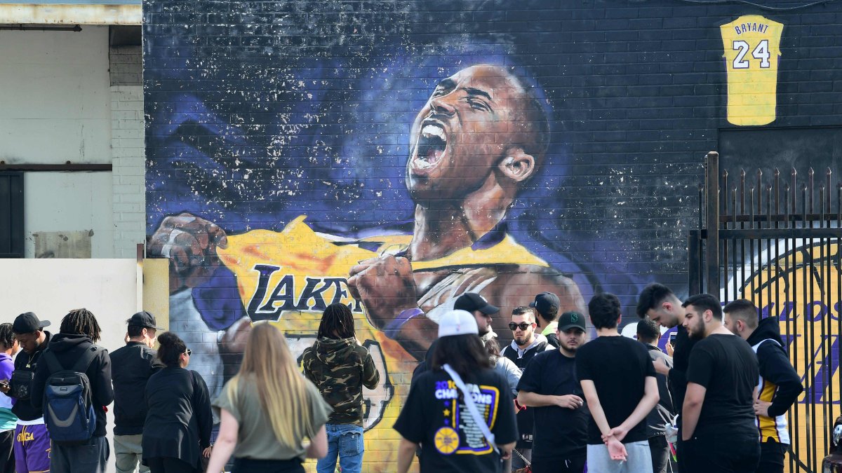 Fanáticos de Kobe Bryant cerca a una imagen de su ídolo, fallecido en un accidente aéreo.