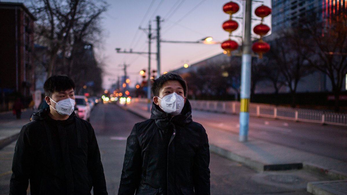 PEKÍN. Una pareja de pequineses caminan por un sector de calles desoladas. Así son los días en la capital china.