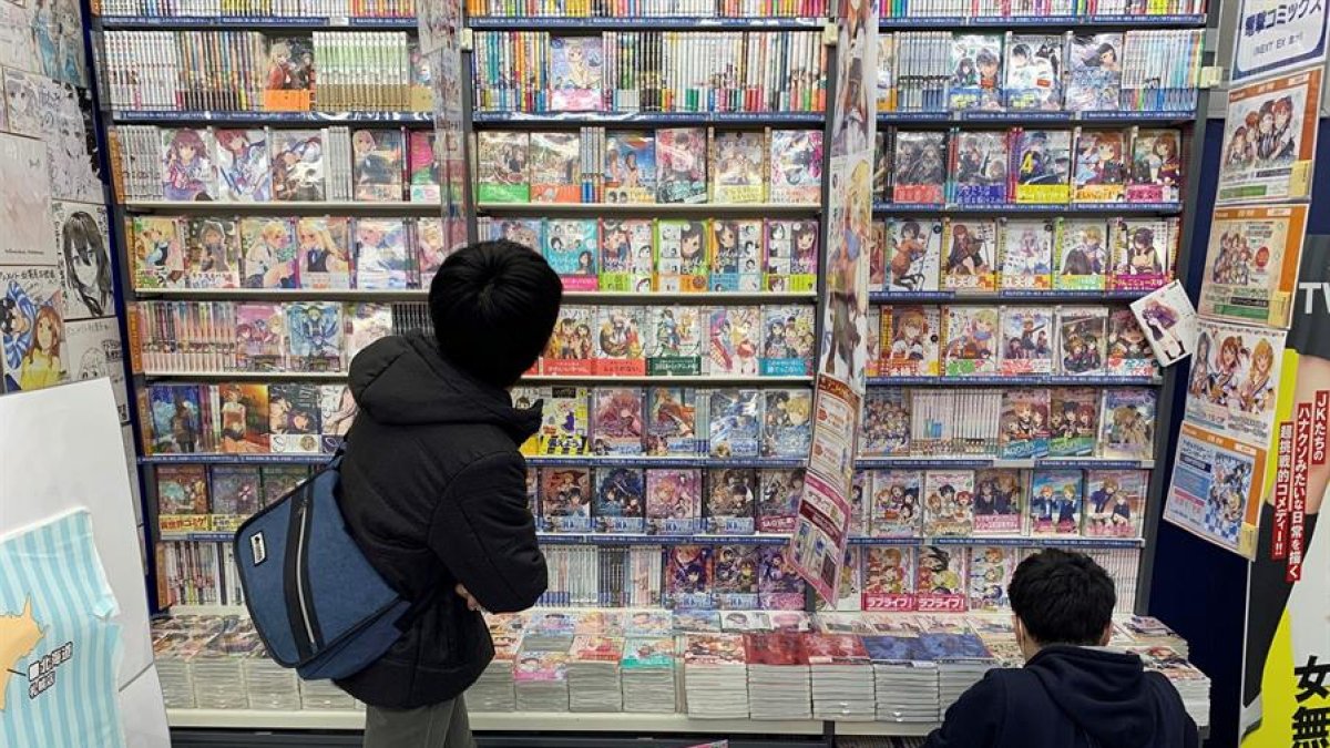 Dos personas observan algunos de los títulos de manga más populares del momento, que son también adaptados a series de anime, en una tienda de Tokio, Japón.