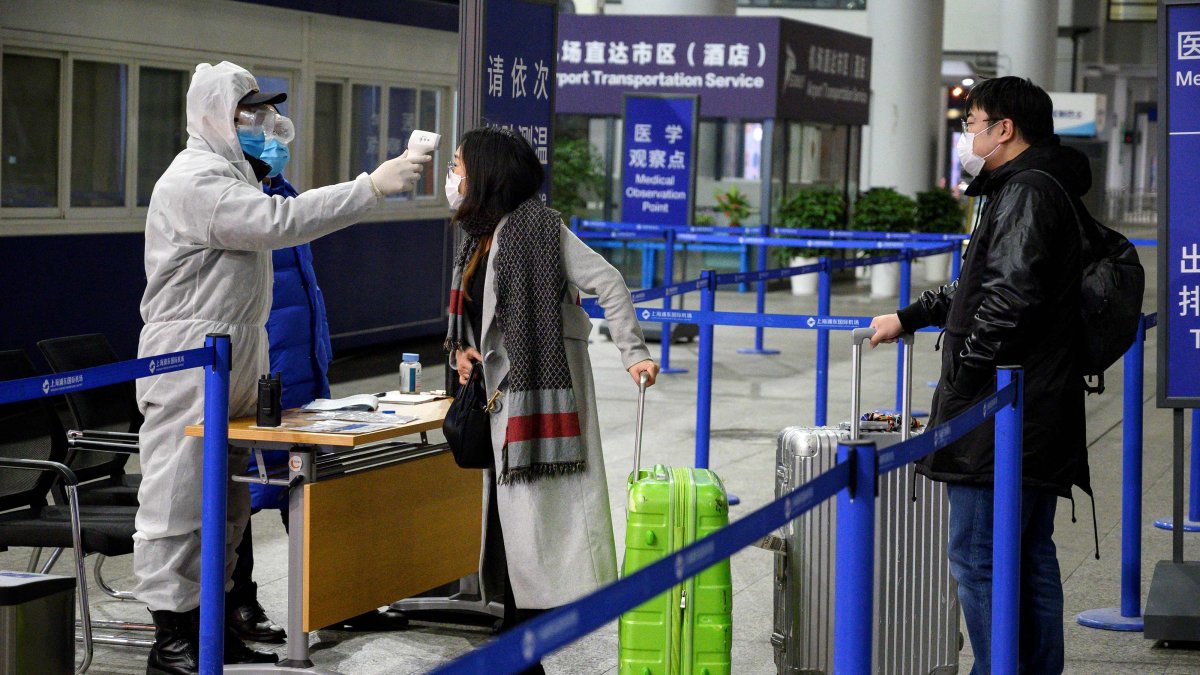 Personal de seguridad verifica la temperatura de los pasajeros que llegan al Aeropuerto Internacional de Shanghai.