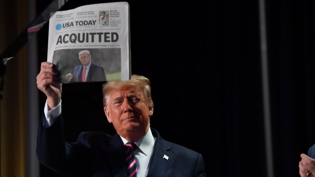 El presidente Donald Trump muestra un periódico que publica la la noticia de su absolución  a su llegada al 68º Desayuno Anual de Oración Nacional.