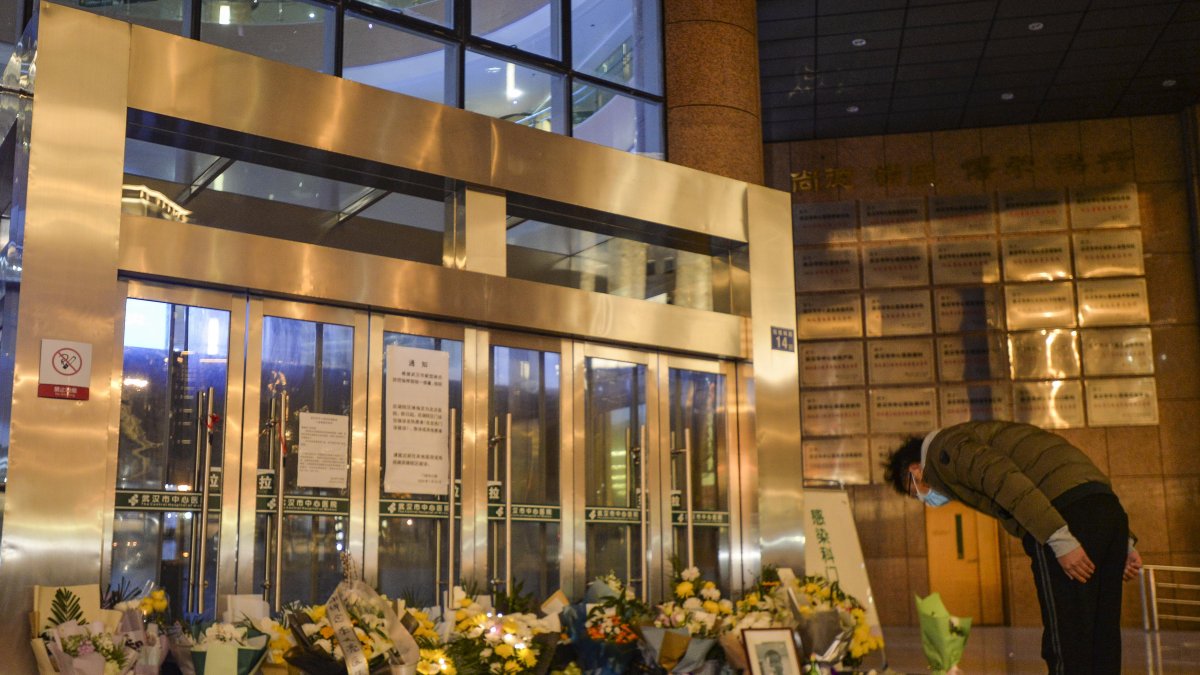 Un ciudadano se inclina frente a un memorial improvisado, para rendir homenaje al Dr. Li Wenliang en el hospital de Wuhan.