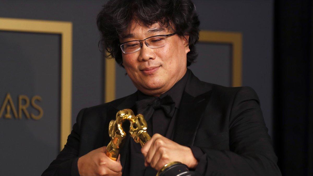Bong Joon Ho juega con sus dos estatuillas por Mejor director y guion.