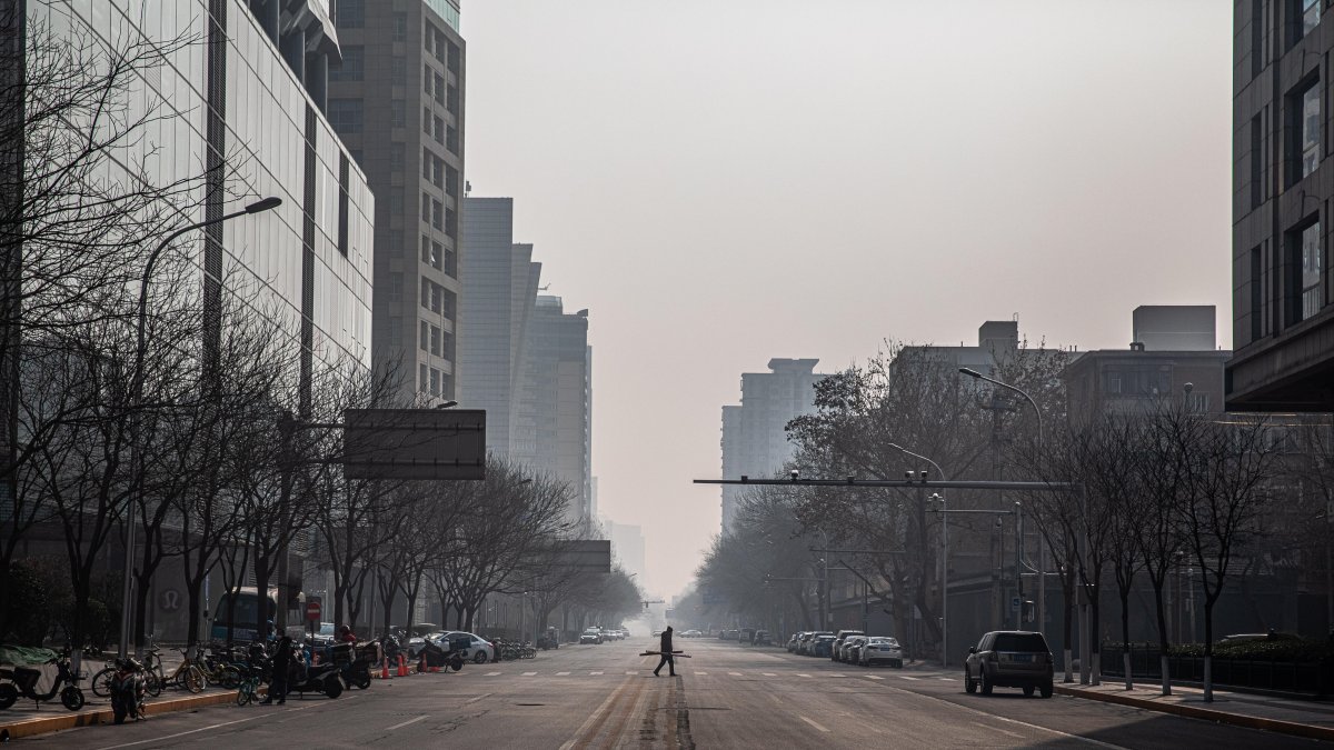 PEKÍN. Una persona transita por una avenida totalmente desolada. El temor y las restricciones aumentan en China, a causa del coronavirus.
