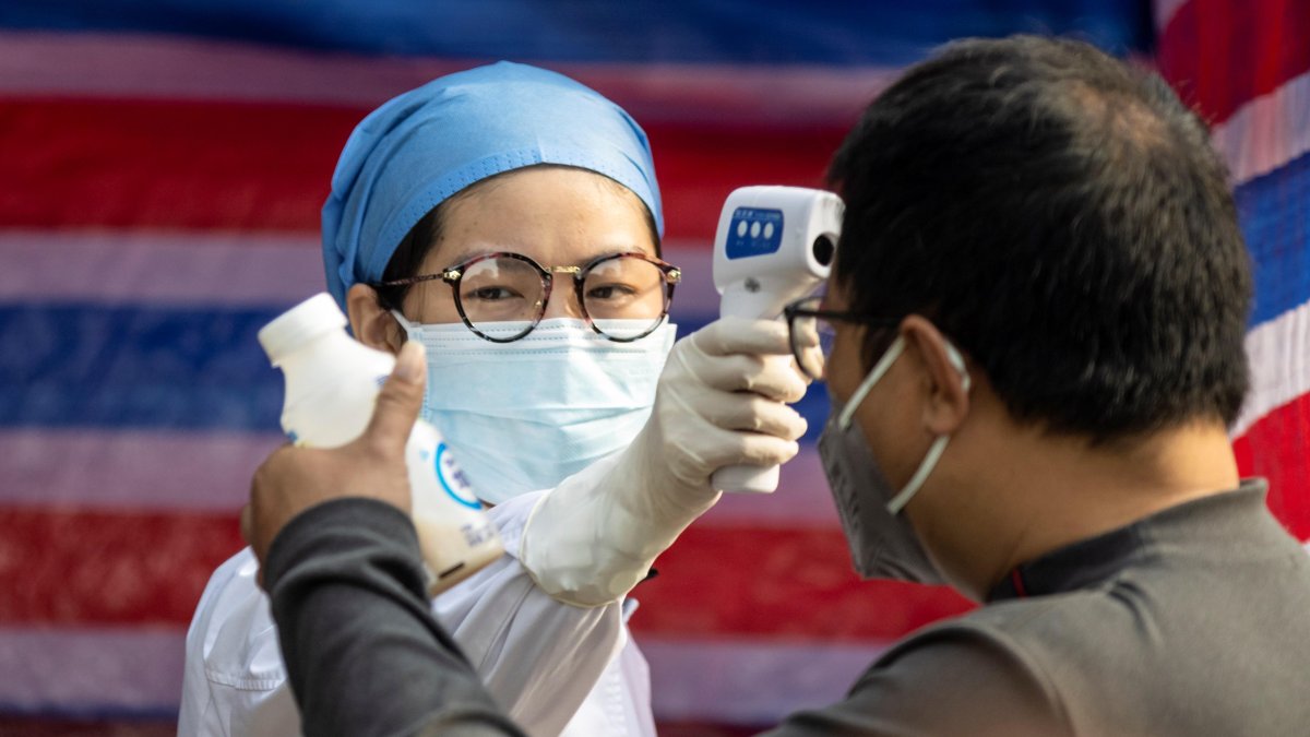 Un miembro del personal médico comprueba la temperatura corporal de un ciudadano en Guangzhou, China.