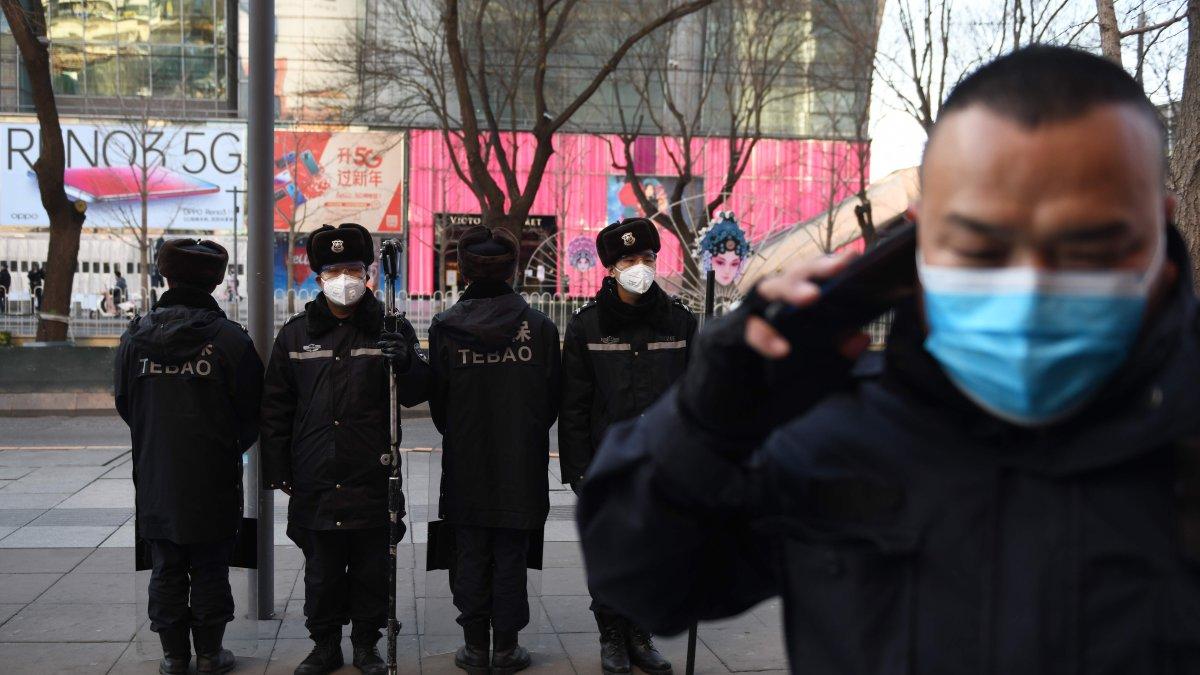 Guardias de seguridad con máscaras faciales protectoras patrullan en una zona comercial en Beijing. 