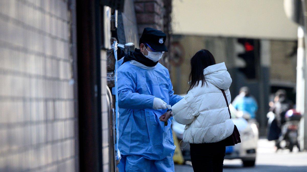 El guardia de seguridad que lleva una máscara protectora controla la temperatura de una mujer antes de ingresar a un hospital en Shanghai