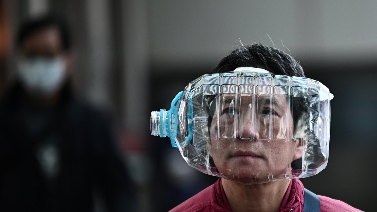 Un hombre usa una botella de agua de plástico  para cubrirse la cara, como medida preventiva contra el nuevo coronavirus.