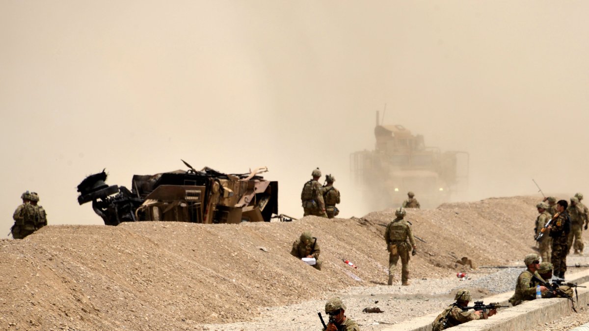 KANDAHAR. Soldados estadounidenses vigilan cerca de los restos de su vehículo en el sitio de un ataque suicida talibán.