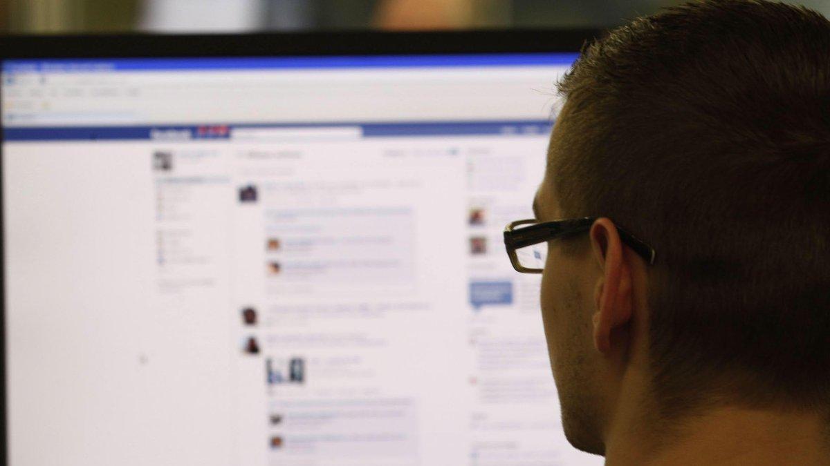 Fotoilustración de un hombre frente a la pantalla de su computadora revisando su cuenta de Facebook