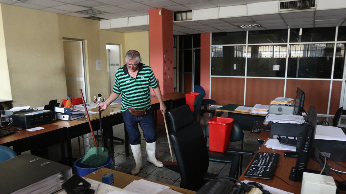 Personal de mantenimiento limpia la oficina de la secretaría general de la carrera de Comercio Exterior, que amaneció inundada.