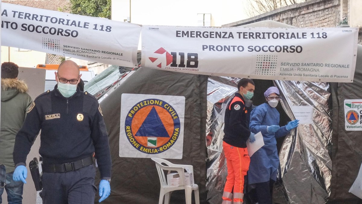 Piacenza. Profesionales de la salud usan trajes protectores y máscaras de atención médica frente a una unidad médica construida fuera de la sala de emergencias del hospital local.
