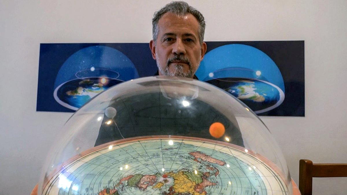 El teórico conspirador brasileño, Anderson Neves, sostiene una maqueta de la tierra plana