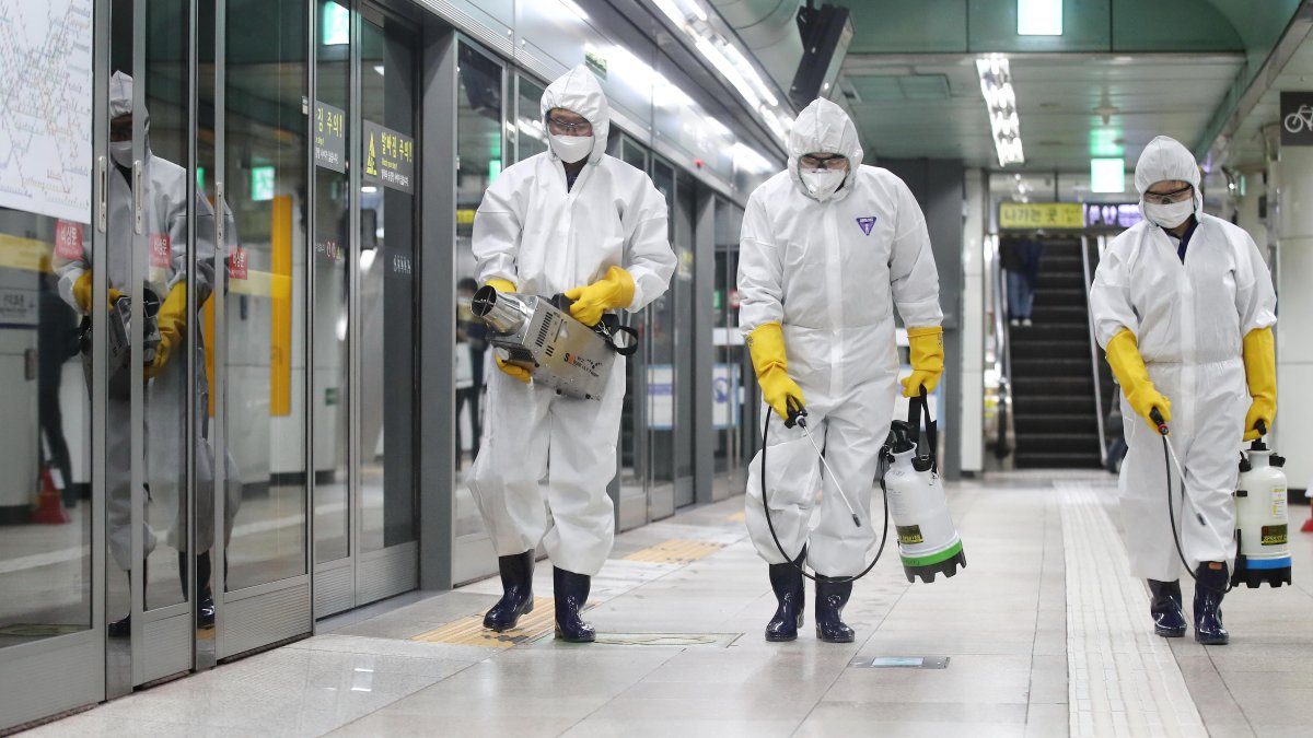 Como medida preventivas contra la propagación del coronavirus COVID-19, un grupo de trabajadores usan desinfectante en aerosol en una estación de metro en Seúl 