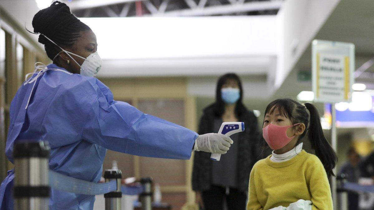 NAIROBI. Un trabajador de la salud de Kenia examina a una niña que arriba en un vuelo desde china en el Aeropuerto Internacional 'Jomo Kenyatta'.