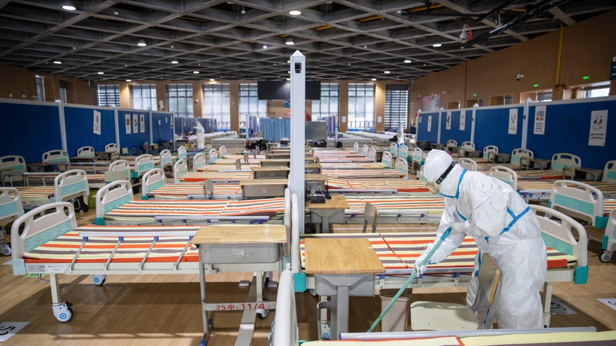 WUHAN. Personal sanitario limpia el piso en un hospital temporal establecido para tratar a las personas con el coronavirus COVID-19, después de que todos los pacientes fueron dados de alta.