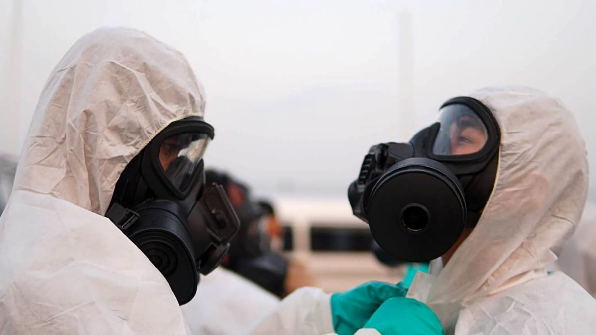 Oficiales de la marina, protegidos con máscaras especiales, se preparan para la llegada de un avión que transportaba a ciudadanos tailandeses evacuados de Wuhan.