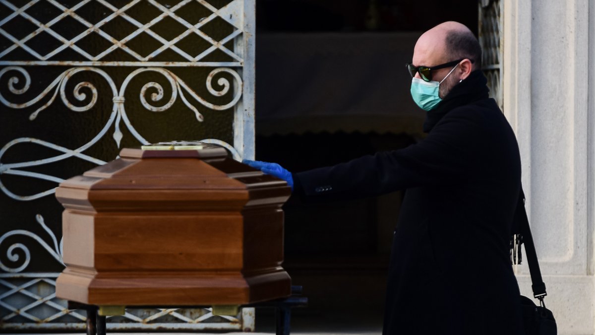 Un hombre toca el ataúd de su madre durante un funeral en el cementerio de Seriate, cerca de Bérgamo, Lombardía
