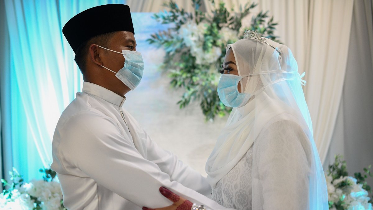 Malaysia. Mohammad Nor Azwan Ishak, de 27 años, y la novia, Nuramiraalia Noorbashah, de 25, usan mascarillas como medida preventiva contra el COVID-19.