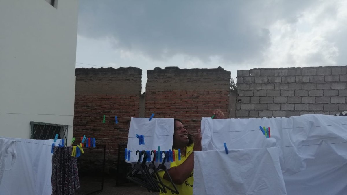 Chinto Espinoza colgando la ropa en el patio de su casa.