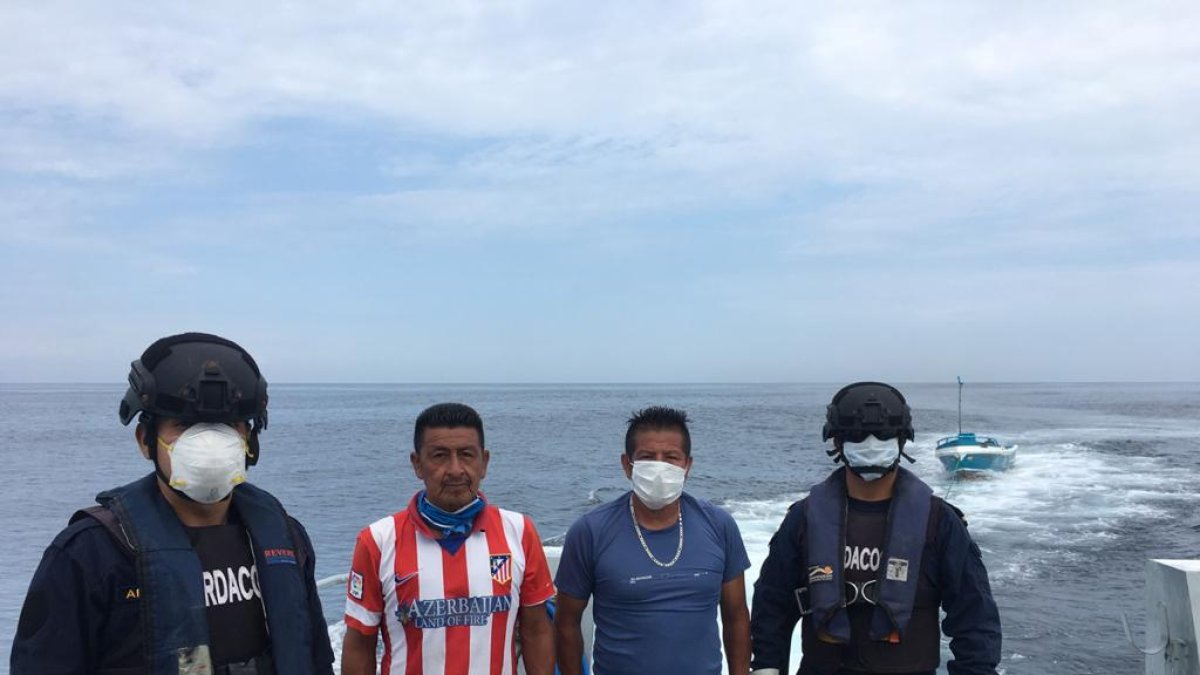 Dos de los pescadores rescatados con marinos de la Armada del Ecuador que los salvaron.