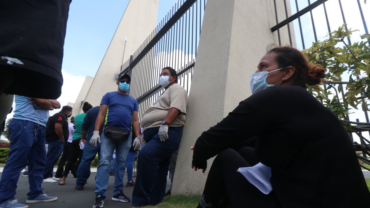 Personas usan mascarillas en el exterior de un cementerio de Guayaquil, a la espera de información de sus familiares fallecidos