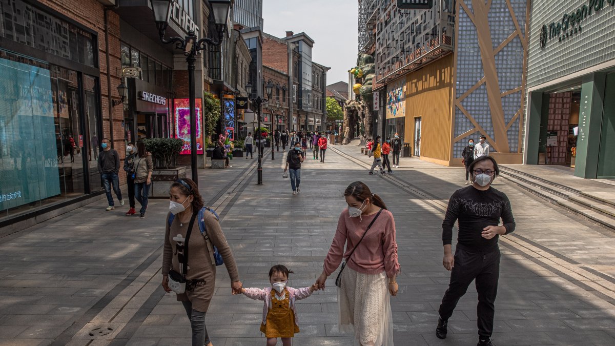 WUHAN. Una faamilia se arriesga a caminar por una de las calles de esta ciudad, tras más de dos meses de cuarentena. Llevan sus rostros protegidos.