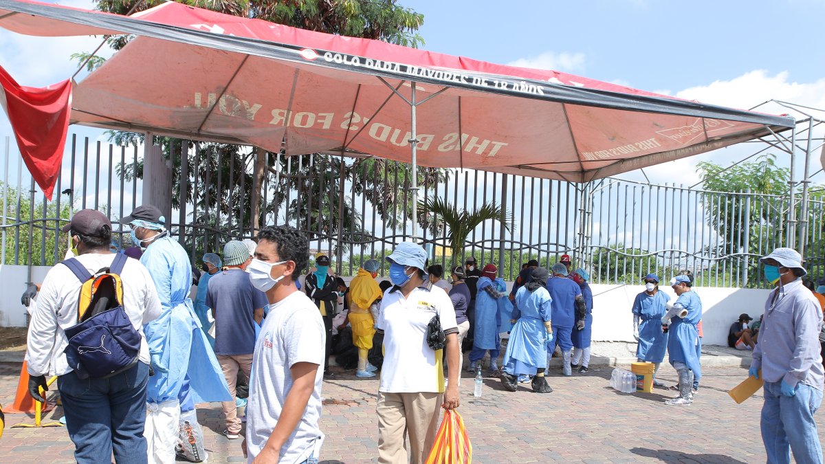 Ciudadanos en el exterior del hospital Guasmo Sur, uno de los centros de tratamiento del COVID-19, usan mascarillas como medida de prevención.