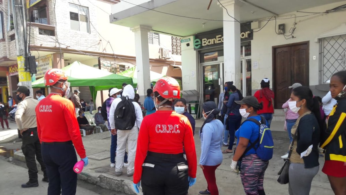 CONTROL. Decenas de personas hacen fila en las afueras de BanEcuador de Pedro Carbo. Lo hacen bajo vigilancia para que se cumpla con las medidas de bioseguridad 