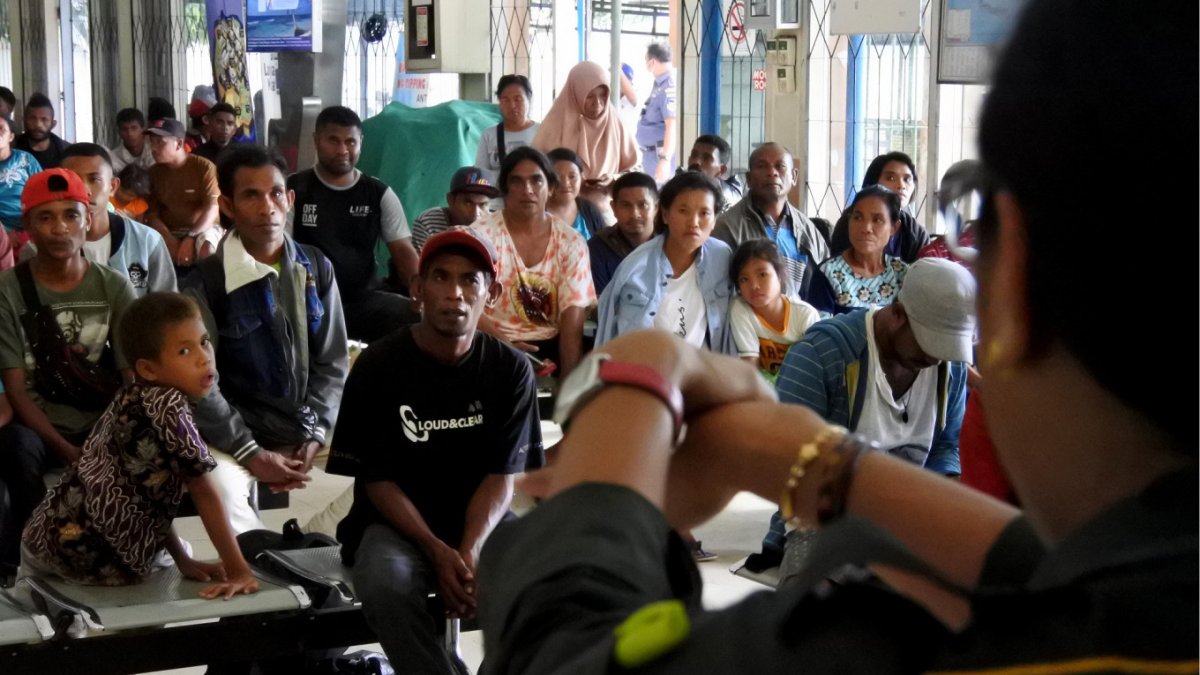 Un funcionario muestra los procedimientos de lavado de manos a los pasajeros que esperan en el puerto de Tenau en Kupang, Indonesia.