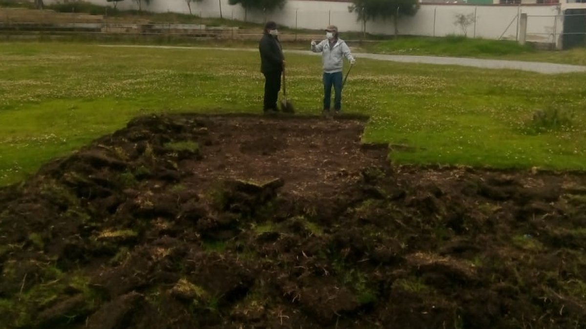 El conserje y el presidente de la liga reparan la cancha, maltratada por las lluvias.