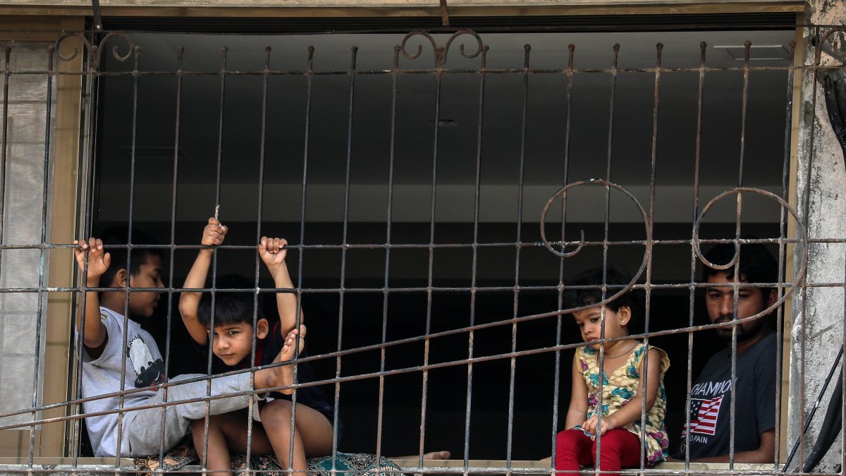 Niños indios miran desde la ventana de su casa en las afueras de Mumbai, India, tras la declaratoria de emergencia 