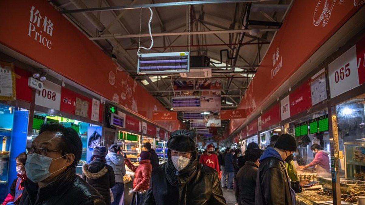 Las personas que usan máscaras protectoras visitan un mercado en Beijing, China